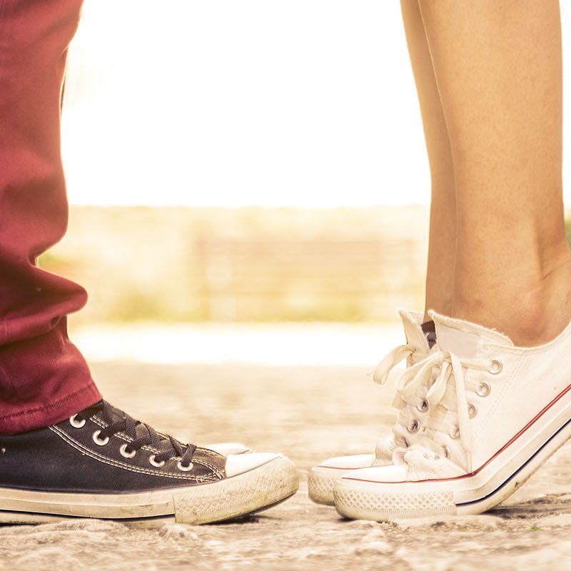Two pairs of feet with one set on tip toes to reach for a kiss