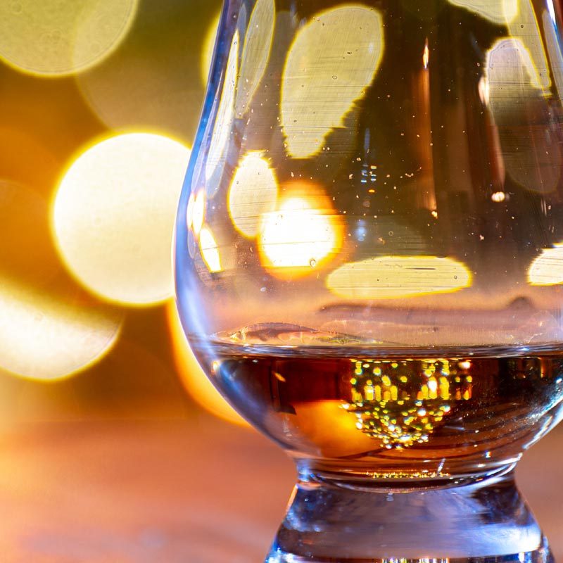Two drams of whisky with festive lights in the background