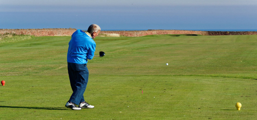 A man swinging his golf club on a golf course
