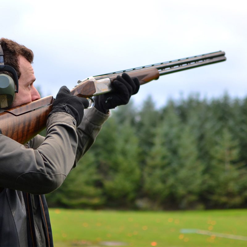 A man with his gun pointed while clay pigeon shooting