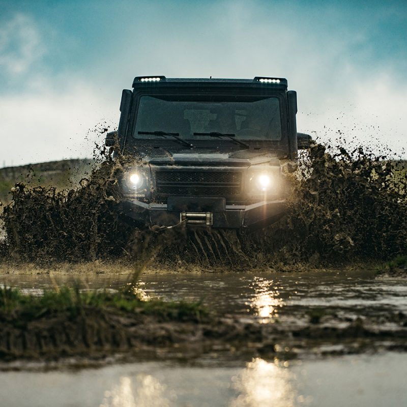 A 4x4 off road driving through a muddy puddle