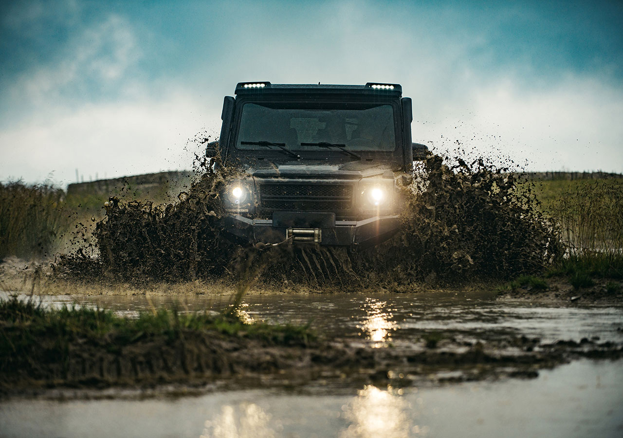 A 4x4 off road driving through a muddy puddle