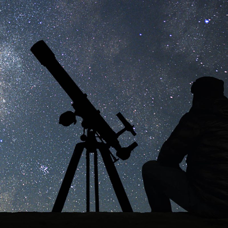 A person with their telescope looking at the stars in the night sky