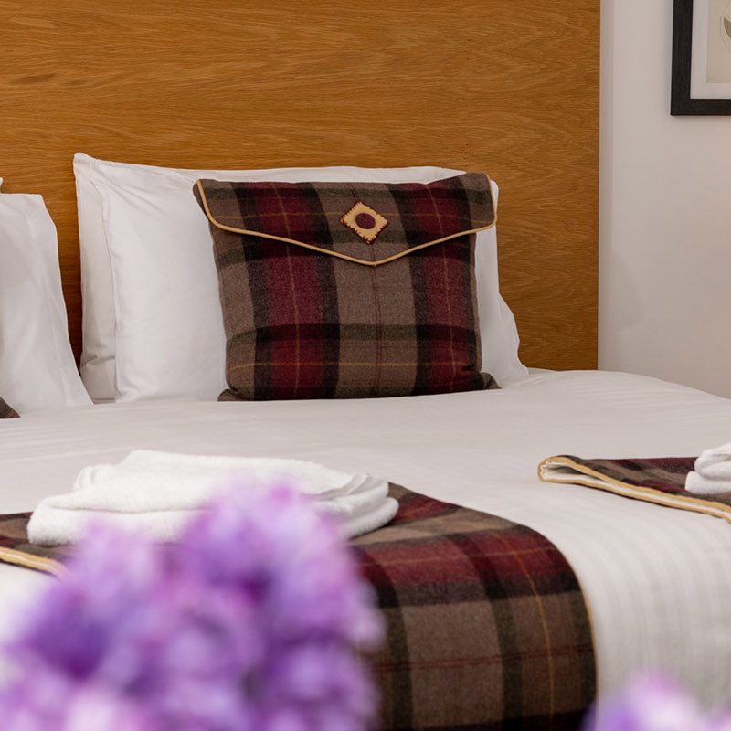 A luxury double bed with purple flowers and lamp in Lodge 3 at Elderburn Luxury Lodges