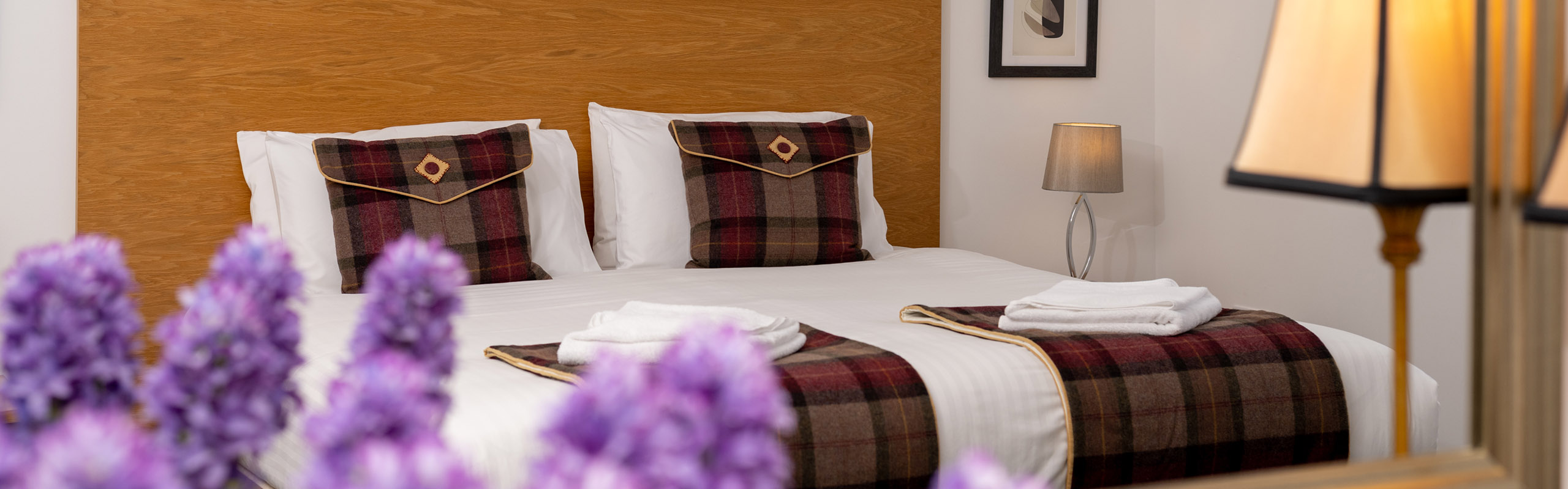 A luxury double bed with purple flowers and lamp in Lodge 3 at Elderburn Luxury Lodges