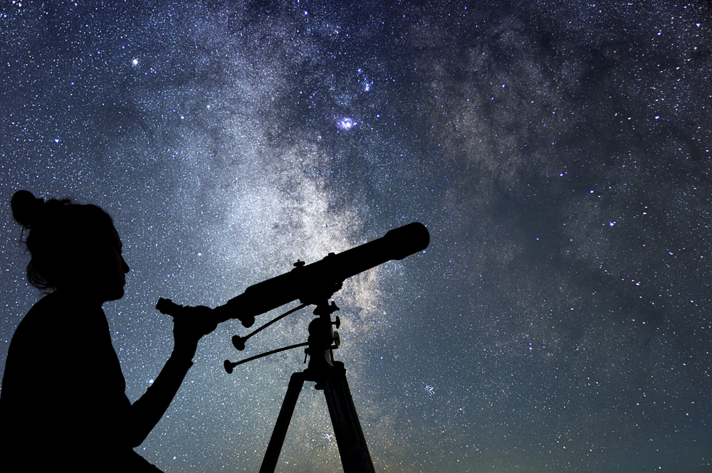 Woman with telescope watching the stars. Stargazing woman and night sky.