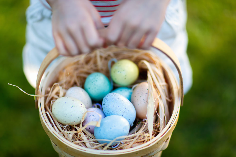 Child holding a basket of colourful eggs